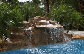 outdoor spa zone with a hardscape waterfall on the edge of the swimming pool