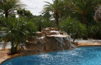 outdoor spa zone with a hardscape waterfall on the edge of the swimming pool