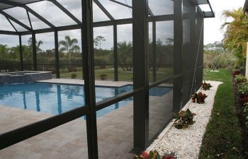 glass enclosed swimming pool with jacuzzi and paver pdeck