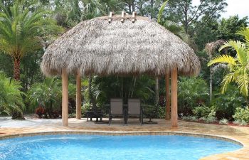 tiki hut with sunbeds on a backyard swimming pool patio