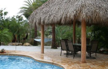 tiki hut with outdoor furniture on a backyard swimming pool Travertine deck