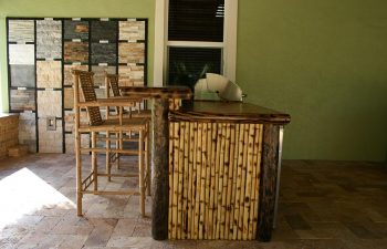 patio with tiki roof and outdoor kitchen and stools by the bar