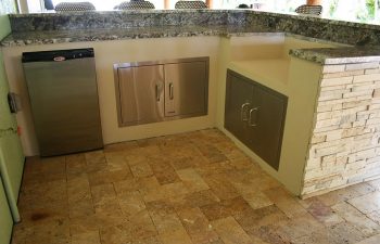 outdoor kitchen with bar and stools under tiki roof