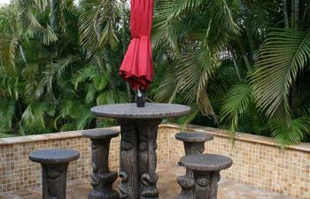 carved table with garden table umbrella and carved stools on a Travertine patio