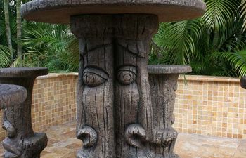 carved table with garden table umbrella and carved stools on a Travertine patio