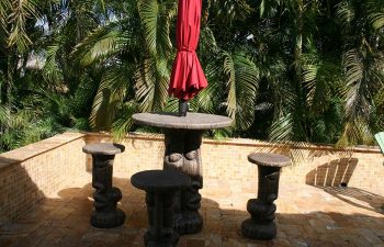 carved table with garden table umbrella and carved stools on a Travertine patio