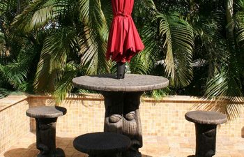 carved table with garden table umbrella and carved stools on a Travertine patio