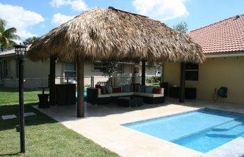 tiki hut and outdoor furniture by a backyard swimming pool