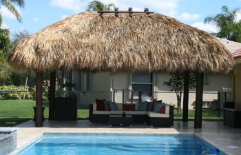 tiki hut and outdoor furniture by a backyard swimming pool