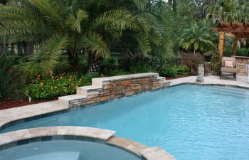 swimming pool with a waterfall in a landscaped garden