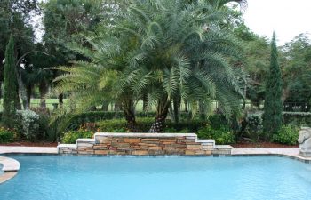 in-ground swimming pool with a waterfall in a landscaped garden