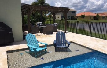 beach entry backyard swimming pool with two sunbeds