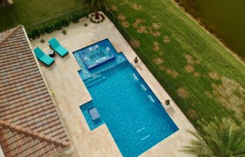 aerial view of backyard swimming pool with water features and sunbeds on a deck