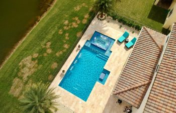 aerial view of backyard swimming pool with water features and sunbeds on a deck