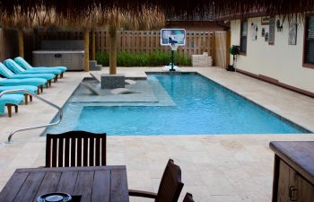 backyard swimming pool with sport equipment and sunbeds on a deck