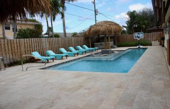 backyard swimming pool with sport equipment and sunbeds on a deck