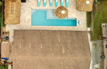 backyard aerial view of a swimming pool with sport equipment and sunbeds on a deck