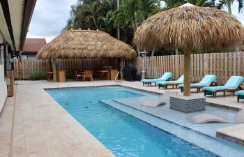 backyard swimming pool with Tiki hut and sunbeds on a deck