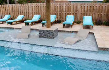 swimming pool with two sunbeds installed in water and classic sunbeds on a deck