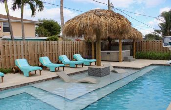 Tiki hut and sunbeds by a backyard swimming pool