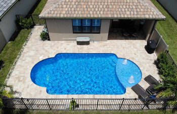 aerial view of a backyard swimming pool with two built-in fountains