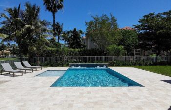 backyard swimming pool with waterfall and three sunbeds on a deck