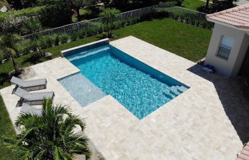 backyard swimming pool with waterfall and three sunbeds on a deck