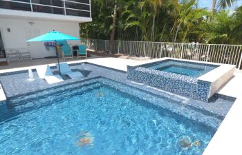 modern backyard swimming pool with jacuzzi and built-in sunbeds