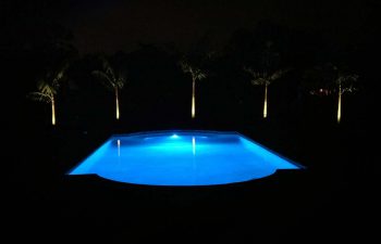 night view of a backyard swimming pool with blue light