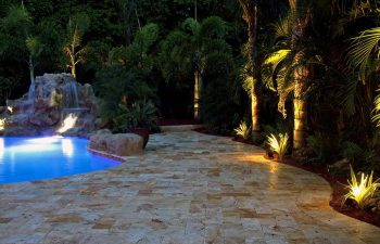 backyard swimming pool with waterfall and Travertine deck at night