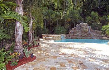 backyard swimming pool with waterfall and Travertine deck