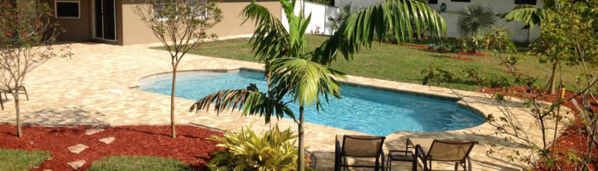 landscaped backyard with a swimming pool and a Travertine paver deck