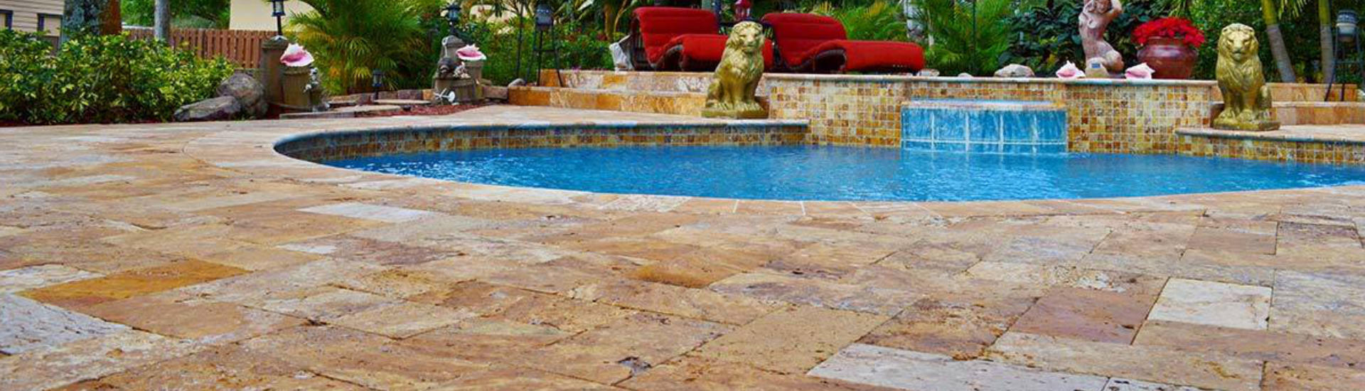 backyard swimming pool with a waterfall and two figures of lions on a deck