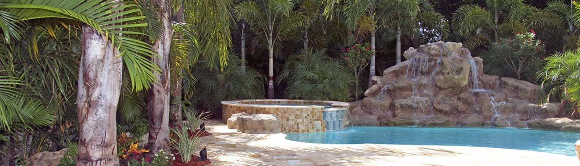 backyard swimming pool with jacuzzi and hardscape waterfall on the edge